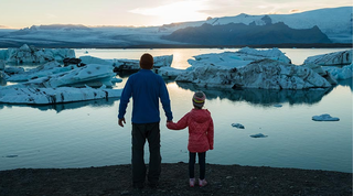 父母和孩子手牵着手看着地平线上的冰山